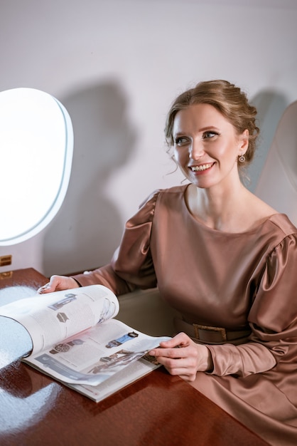 Happy stylish woman sitting in a private plane to the window