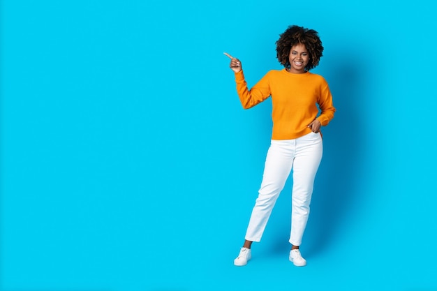 Happy stylish young african american woman pointing at copy space