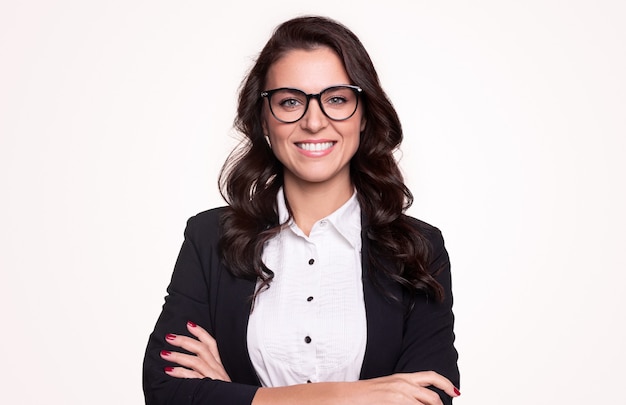 Happy successful adult businesswoman in formal outfit and stylish glasses smiling and looking while standing with arms crossed