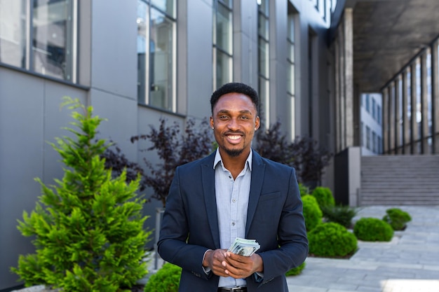 Photo happy successful african american businessman counts, waves, throws, show off, flaunt, cash money background a modern office building looking at camera celebrate winner success in betting stock market