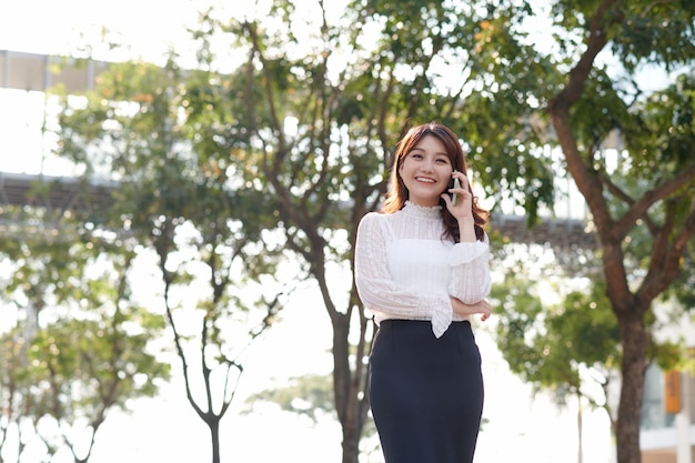 Happy successful businesswoman calling with cell telephone\
outside