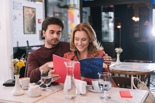 Happy successful couple reading menu and posing at table