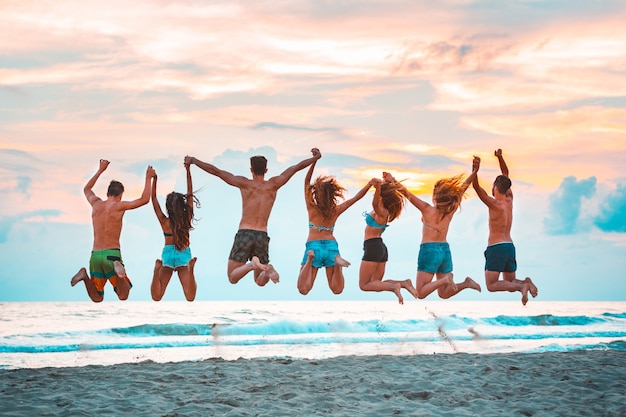 Photo happy successful friends jumping on the beach