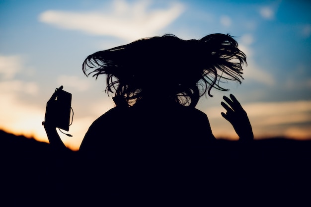 Happy successful sportswoman raising arms to the sky on golden back lighting sunset summer. Copy space.