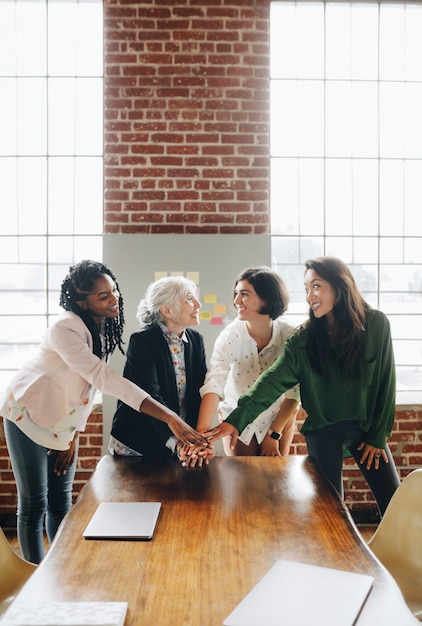 Donne di successo felici che si accatastano le mani