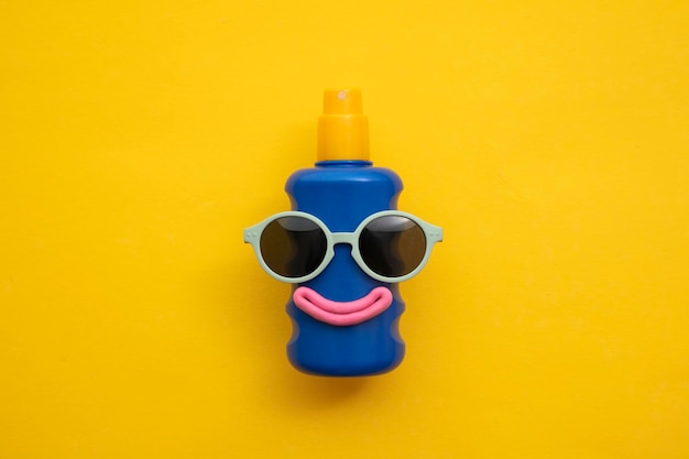 Happy sun block bottle wearing sunglasses and a smile on a yellow background.