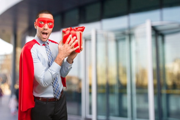 Happy super businessman with a gift