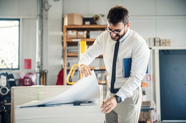 A happy supervisor looking at sheets at printing shop