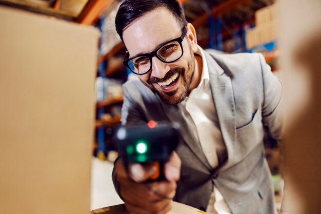 A happy supervisor using qr and bar code scanner on boxes in storage