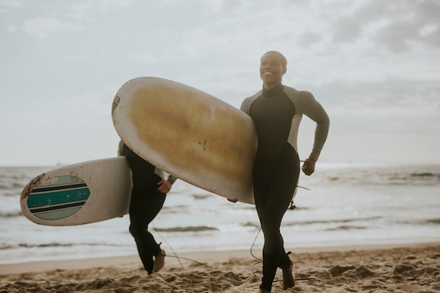 Foto felici surfisti che corrono sulla spiaggia