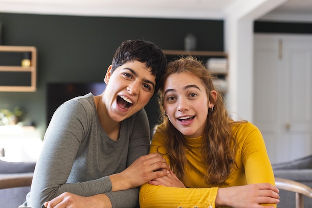 Happy surprised biracial lesbian couple sitting at home having video call