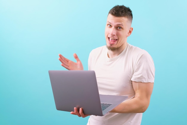 Happy surprised caucasian man holding laptop and looking at the camera on a blue Emotional Smiling