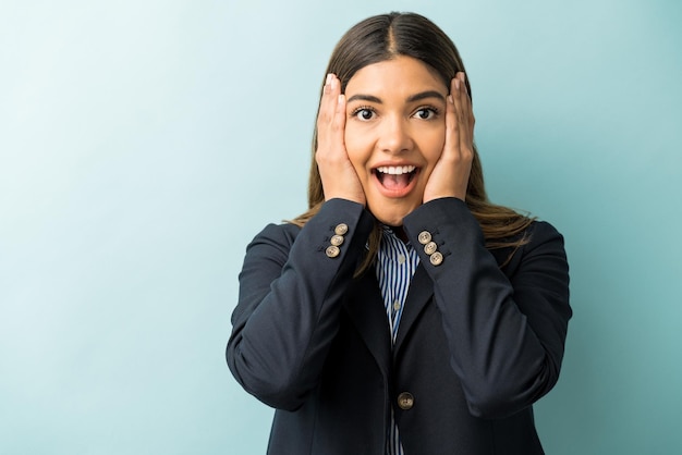 Happy surprised female entrepreneur making eye contact with head in hands against isolated background