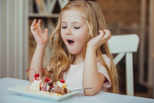 Foto bambina sorpresa felice che serve la coppa di gelato nel tuo caffè.