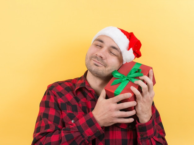 Happy surprised man in a red hat holding a gift with admiration on his face