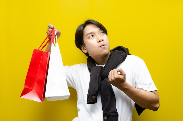 happy surprised young asian man holding shopping bags in excitement