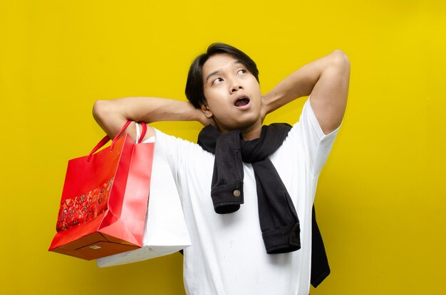 happy surprised young asian man holding shopping bags in excitement