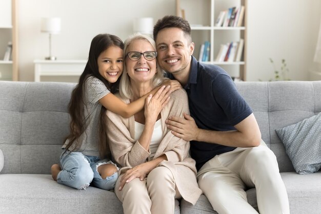 幸せな甘い孫娘の子供と若い父親が愛する祖母を抱きしめる