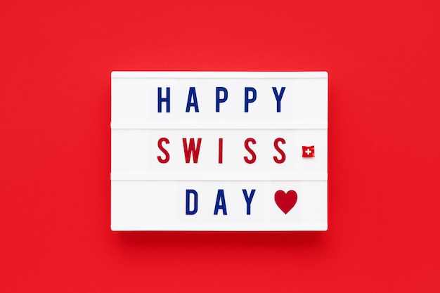 HAPPY SWISS DAY written in a lightbox on a red background.