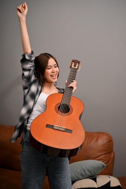 Photo happy and talented young asian female musician holding aher acoustic guitar