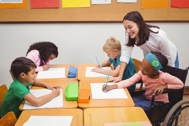 Happy teacher helping her students at the elementary school