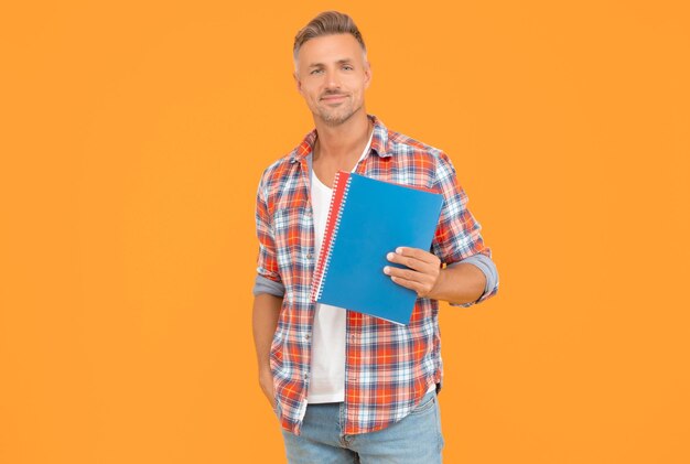 Happy teacher man holding school books for education yellow background copy space