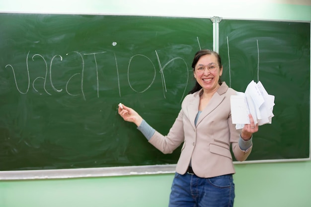 Happy teacher writes the word vacation on the blackboard