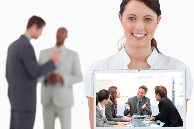 Happy team laughing together at a meeting against tradeswoman showing laptop with colleagues behind her