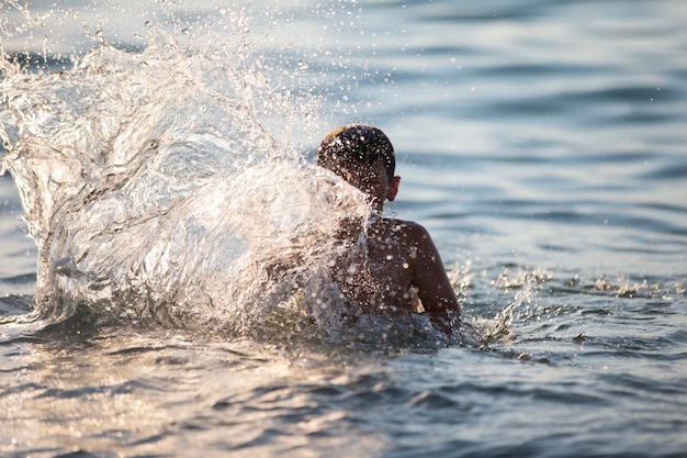 幸せな十代の少年が海の波と遊ぶ 少年は海で泳ぐ