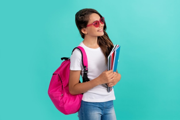 Happy teen girl carry backpack and notebook back to school knowledge day education kid in glasses hold copybook september 1 childhood student child with school bag going to do homework