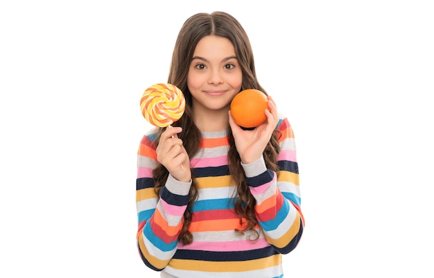 Happy teen girl in colorful sweater with orange fruit and lollipop isolated on white dental care