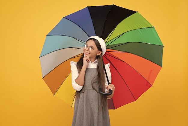 Happy teen girl under colorful umbrella for rain protection in autumn season rainy weather