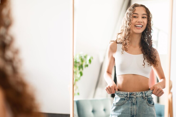 Photo happy teen girl comparing slimmed waist in mirror at home