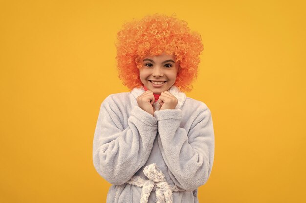 Happy teen girl in fancy orange wig hair wear home bathrobe home wear