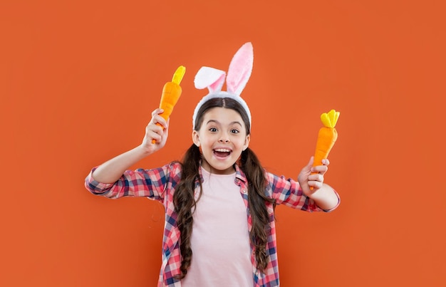 Happy teen girl in funny bunny ears for easter holiday hold carrot easter fun