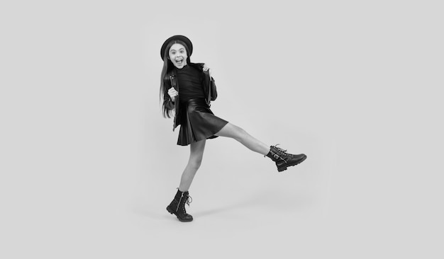 Happy teen girl in hat and leather clothes making wide step forward go forward