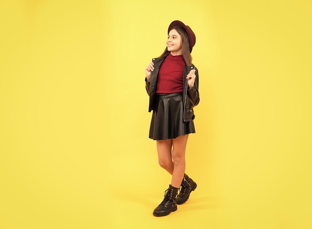 Happy teen girl in hat and leather clothes trend