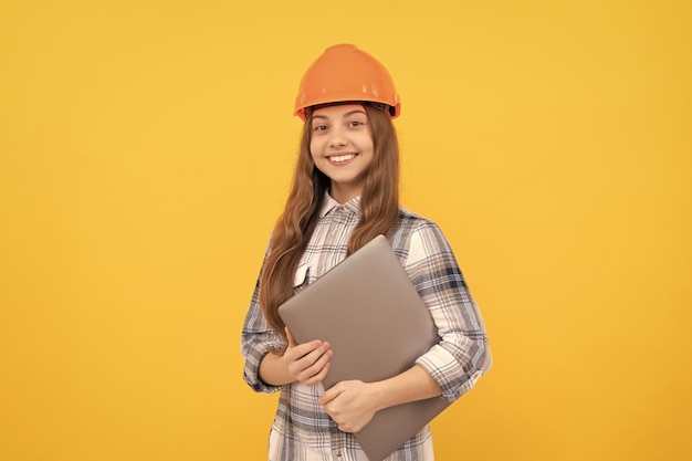 Happy teen girl in helmet and checkered shirt holding computer modern life