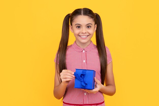 Happy teen girl hold gift box on yellow background boxing day