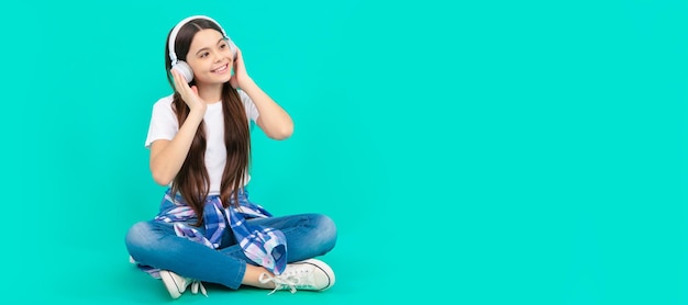 Happy teen girl listen to music in wireless headphones Child portrait with headphones horizontal poster Girl listening to music banner with copy space