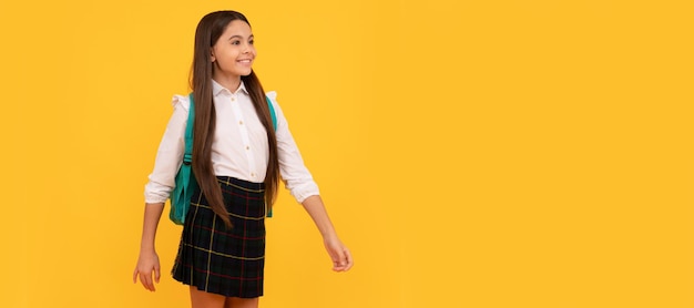 Photo happy teen girl in school uniform full length on yellow background making step forward school