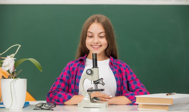 Happy teen girl using microscope back to school study biology chemistry laboratory