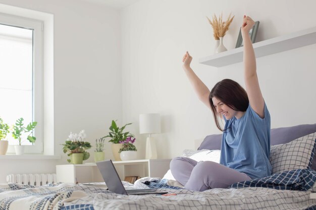 Happy teen girl with laptopat home on bed