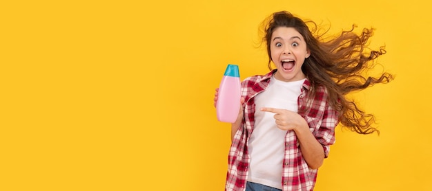 Happy teen girl with long curly hair hold shampoo bottle hairdresser Banner of child girl hair care studio poster header with copy space