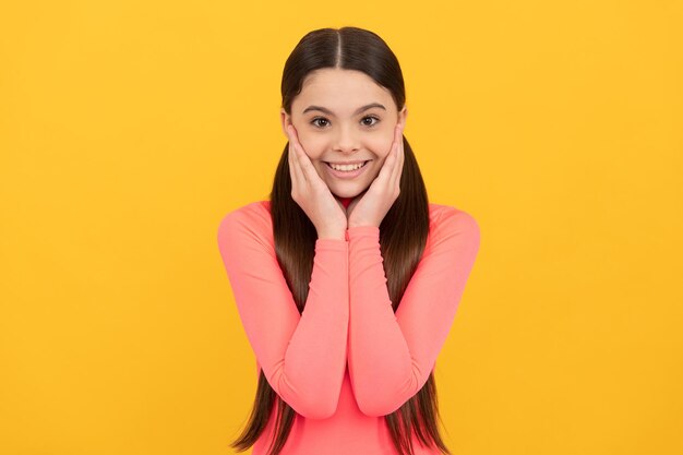 Happy teen girl with long hair on yellow background skincare