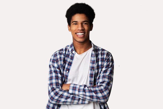 Happy teen guy posing with crossed hands over white background