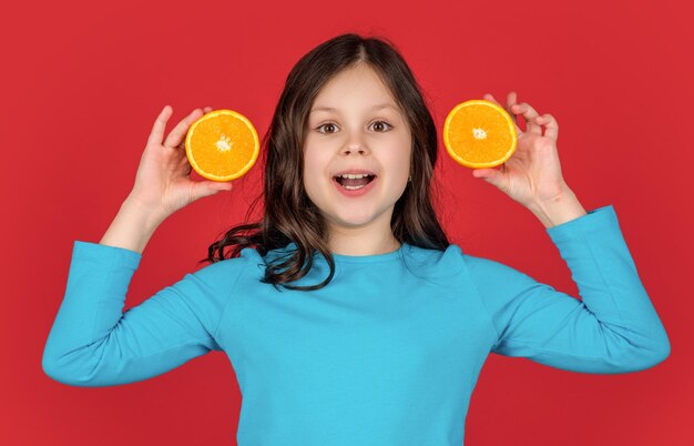 Happy teen kid holding orange fruit on purple background