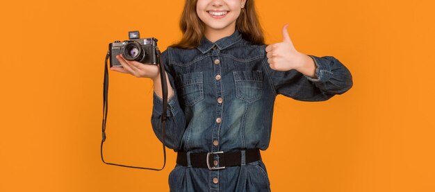 Photo happy teen photographer crop view giving thumb up approval sign holding camera yellow background