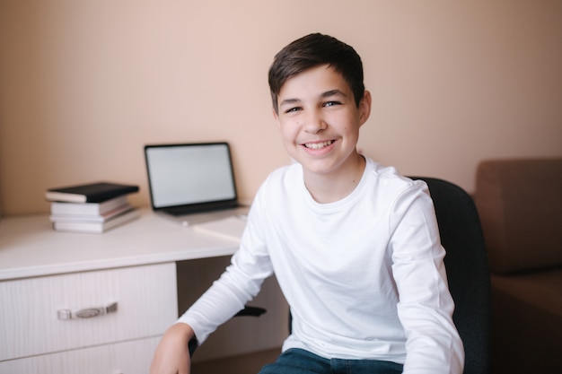 Happy teenage boy sits at his desk