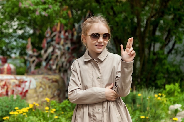 Happy teenage emotion girl in casual clothes and sunglasses on city street. Summer city walks near house. Concept of childhood and parenting. Copy space